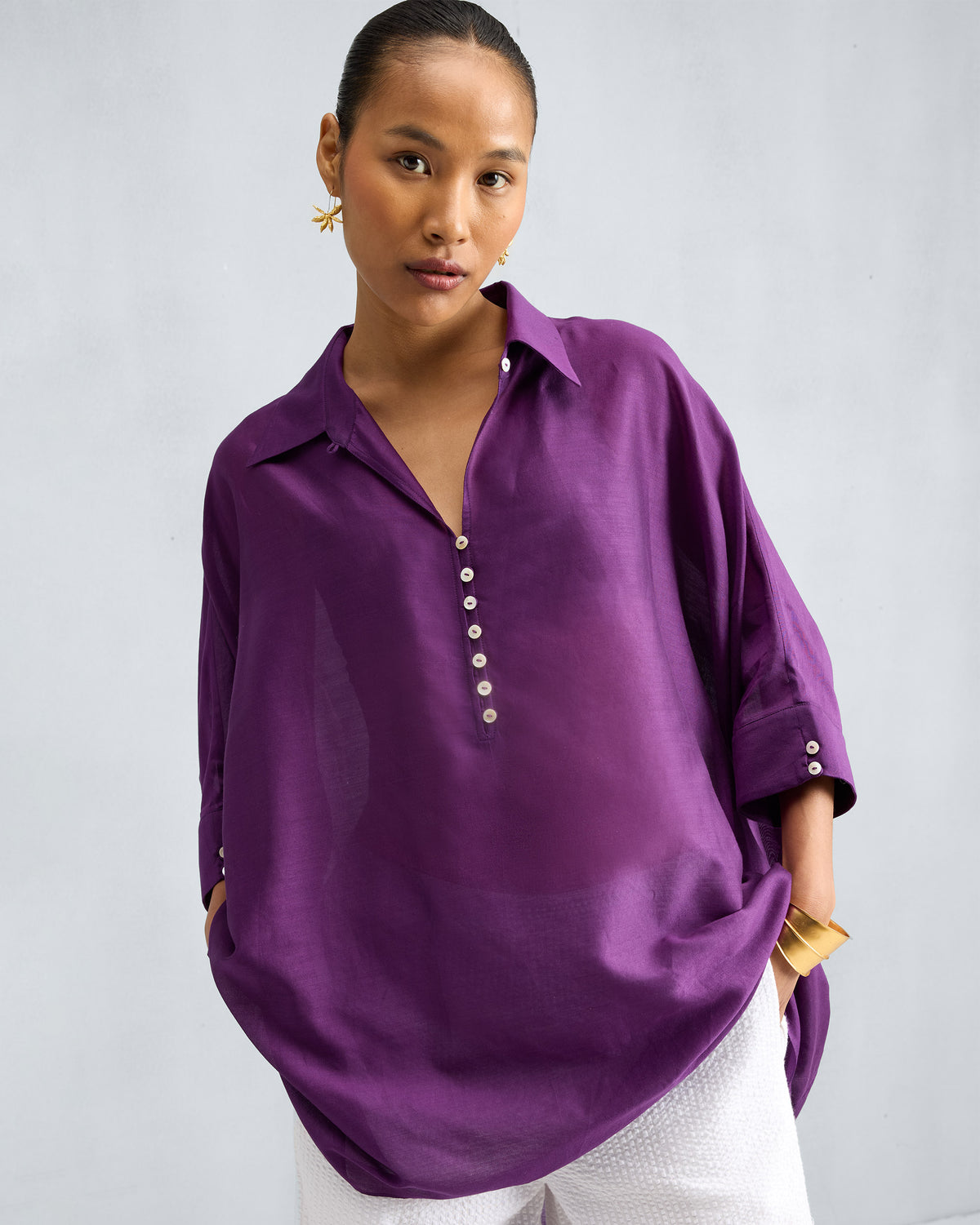 Person wearing a purple Hala Tunic with buttoned cuffs on the sleeves.