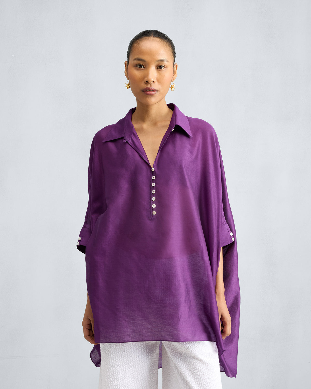 Person wearing a purple Hala Tunic with a collar and a button placket.