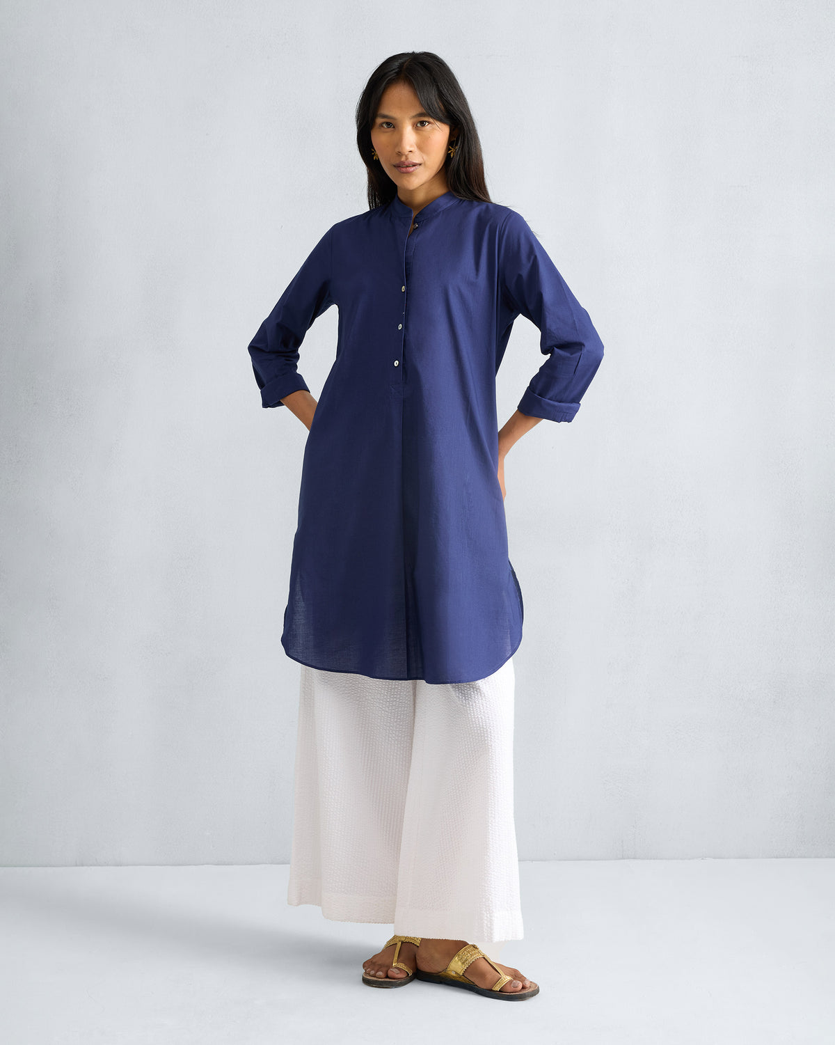 Person wearing an ink blue mid-length kurta with mandarin collar and buttoned placket.
