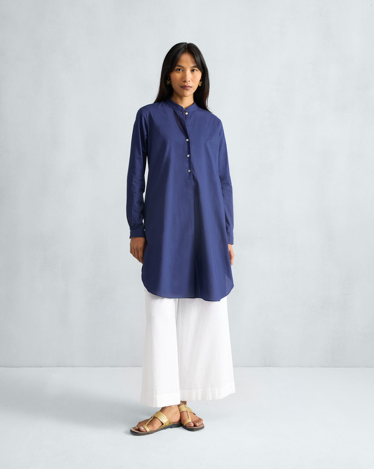 Person wearing an ink blue mid-length kurta with full sleeves and a curved hem.