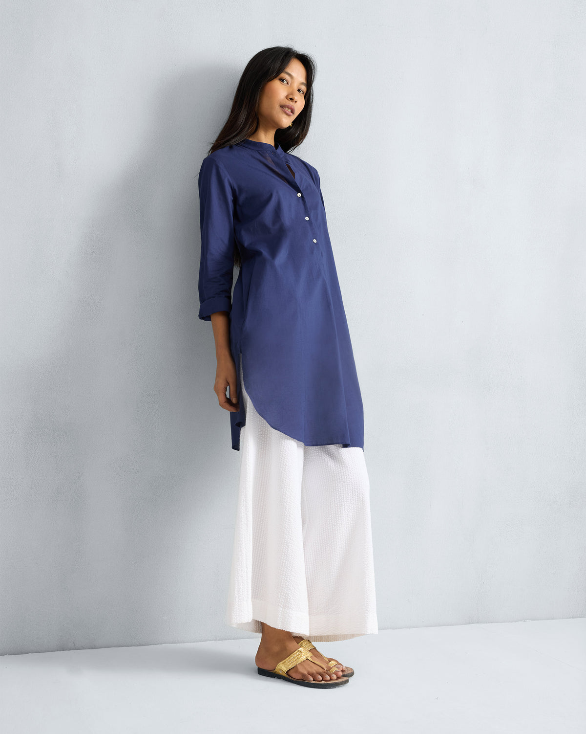 Three-quarter view of an ink blue mid-length kurta showing the curved side hem.
