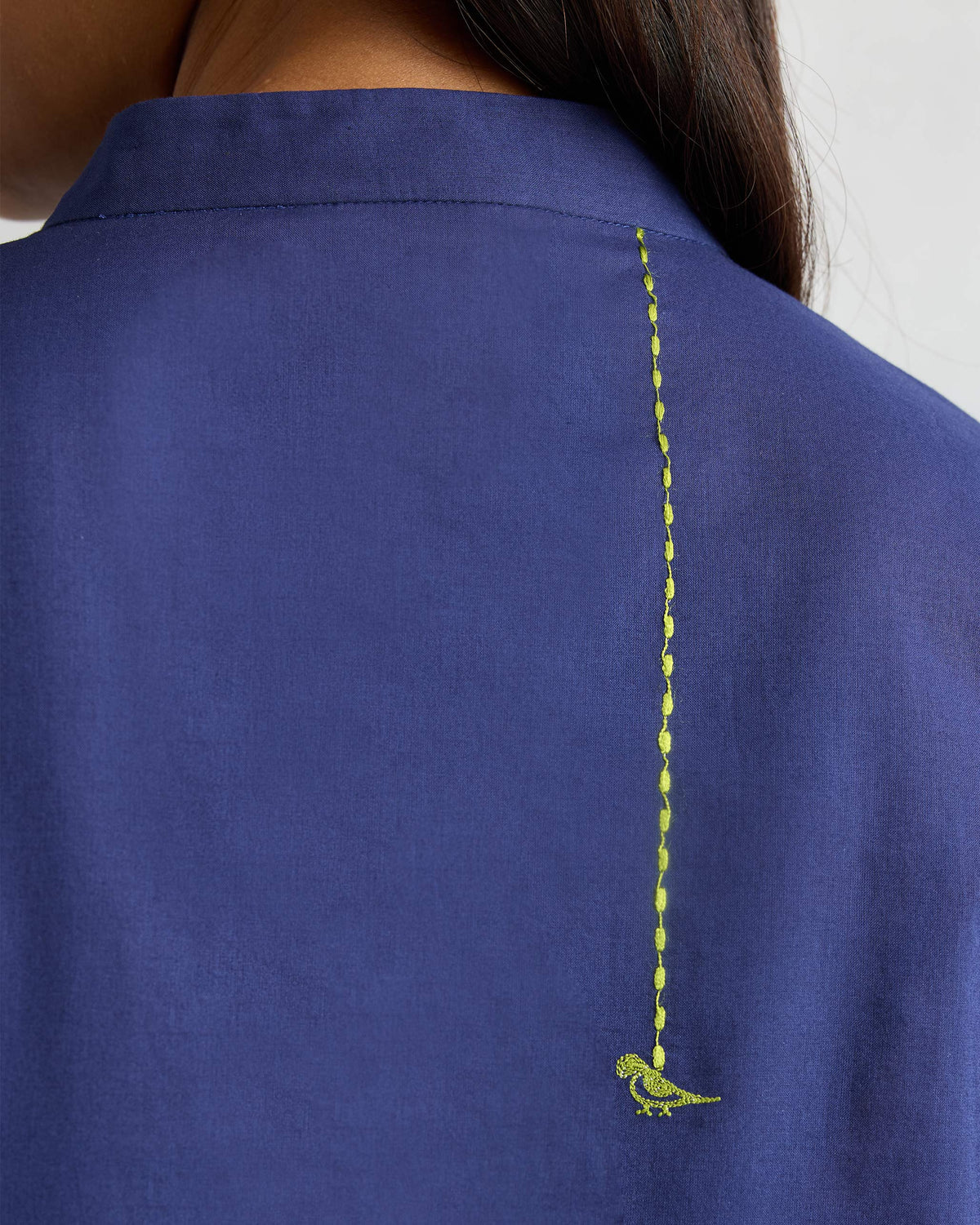 Close-up of a green embroidered parrot on an ink blue kurta.