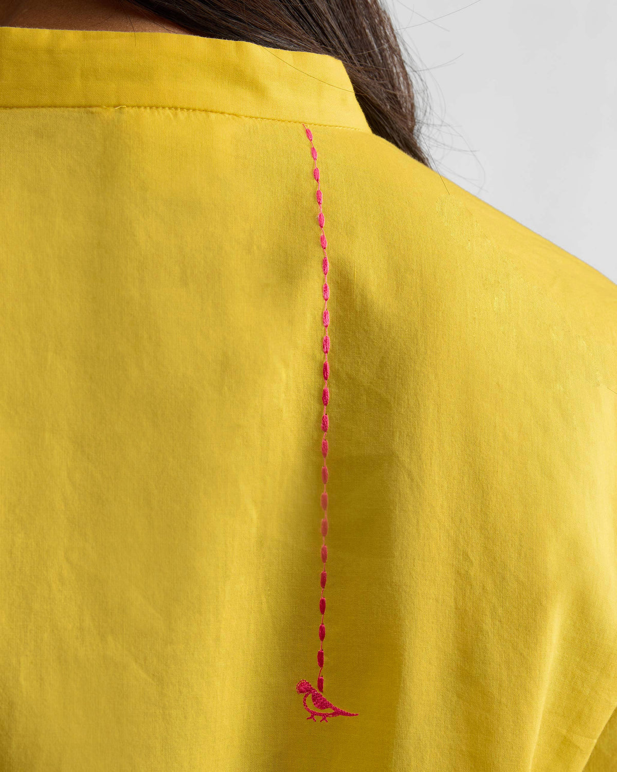 Close-up of a pink bird embroidery on a yellow Basic Long Kurta.
