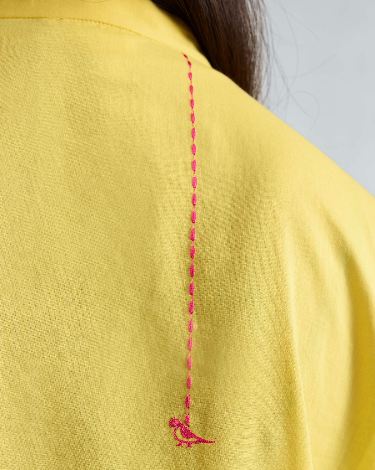Close-up of pink bird embroidery on the back of a yellow Basic Long Kurta.