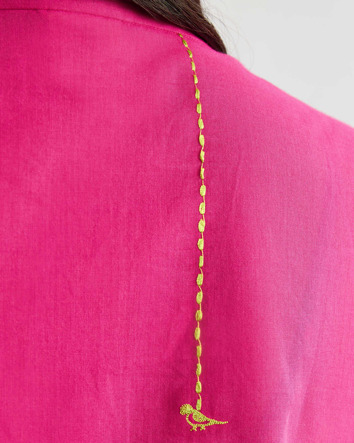Close-up of a lime green bird embroidery on a fuchsia Basic Long Kurta.
