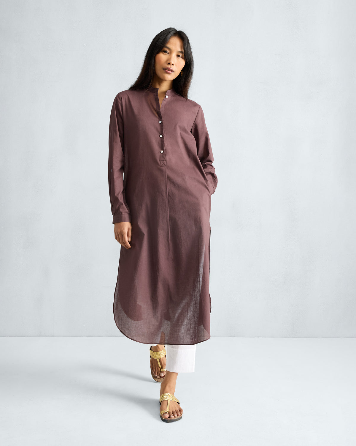 Person wearing a chocolate plum long kurta showing the curved hem and side pocket.