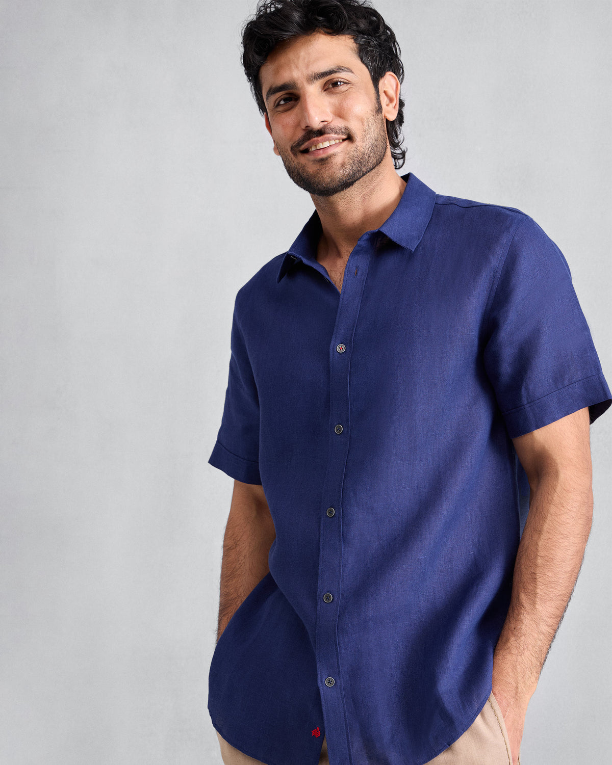 Person wearing an ink blue half-sleeve shirt with red hem embroidery.