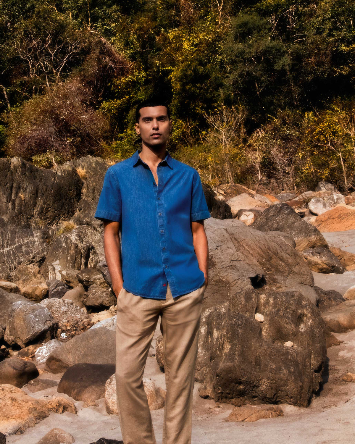 Person wearing a blue denim half-sleeve shirt with red hem embroidery.