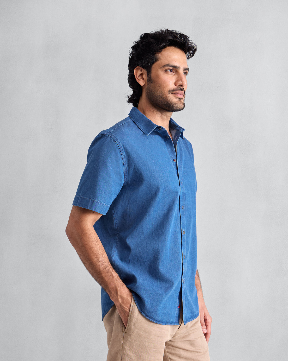 Person wearing a blue denim half-sleeve shirt over beige trousers.