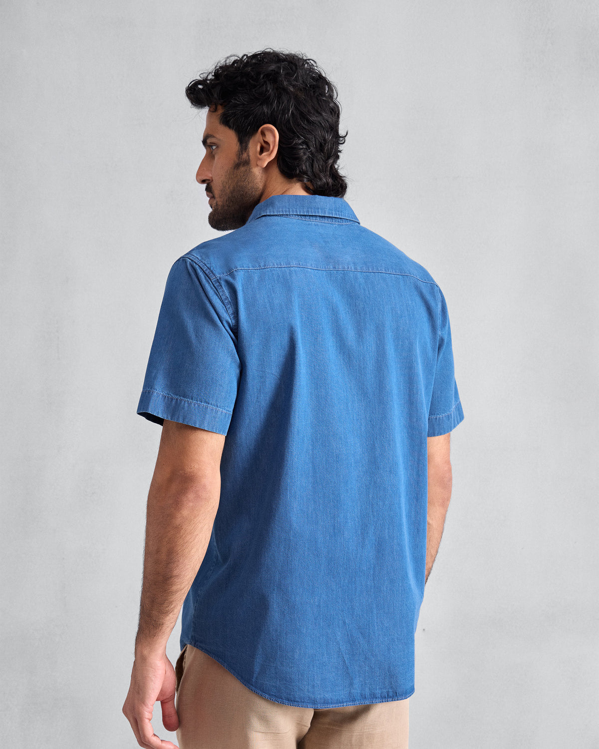 Back of a blue denim half-sleeve shirt worn by a person.