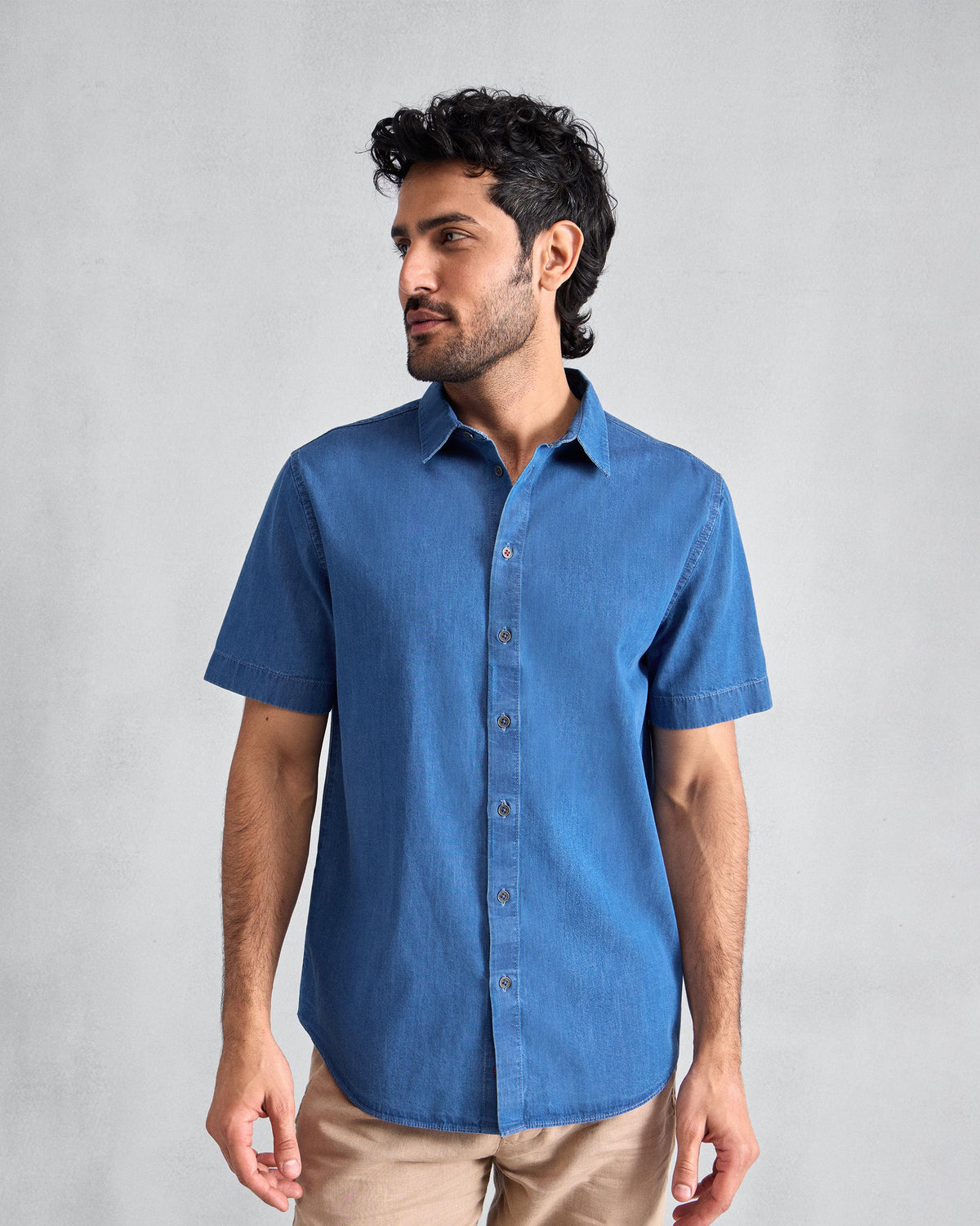 Person wearing a blue denim half-sleeve shirt with a classic collar.