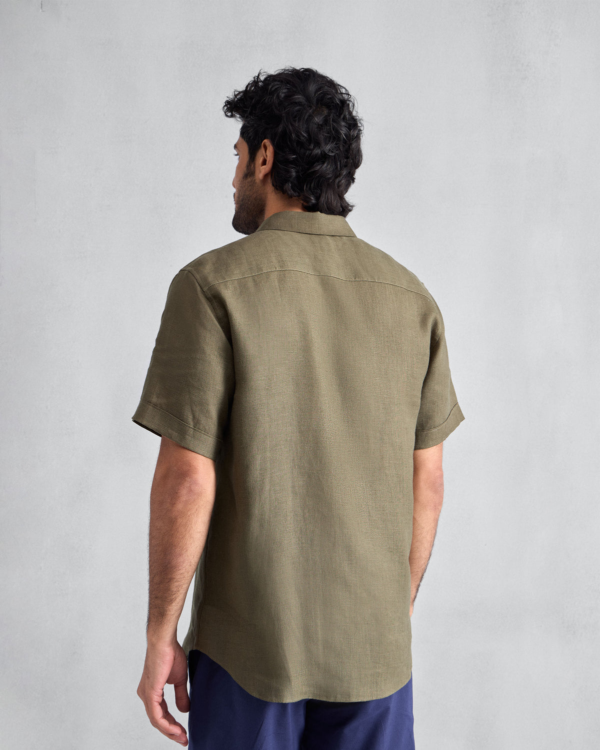 Back of an olive half-sleeve linen shirt showing the yoke and sleeve length.
