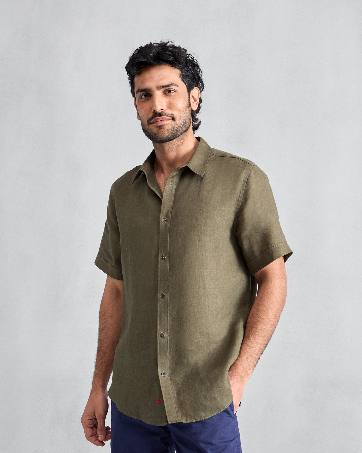 Person wearing an olive half-sleeve linen shirt with a pointed collar and placket.