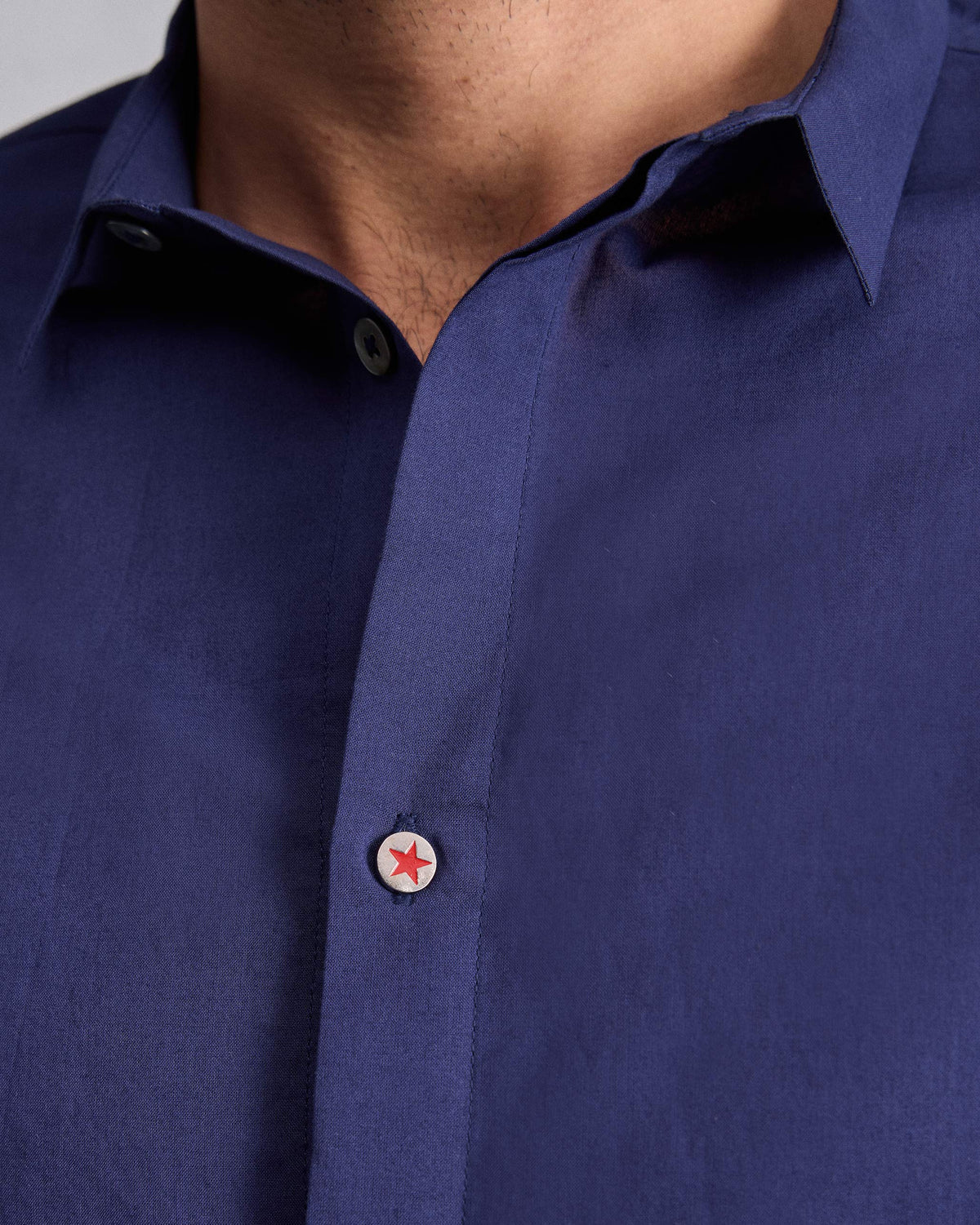 Close-up of an ink blue Riverine Shirt collar with a red star button.