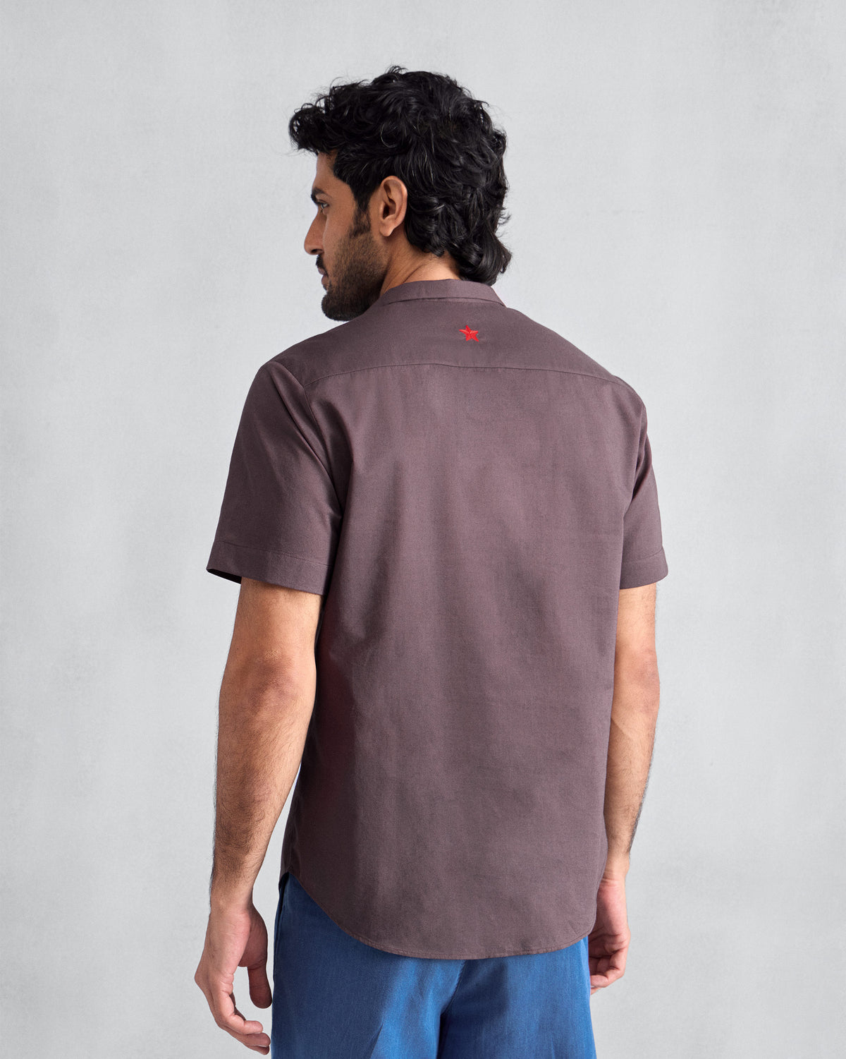 Back of a chocolate plum Riverine shirt with a red embroidered star.