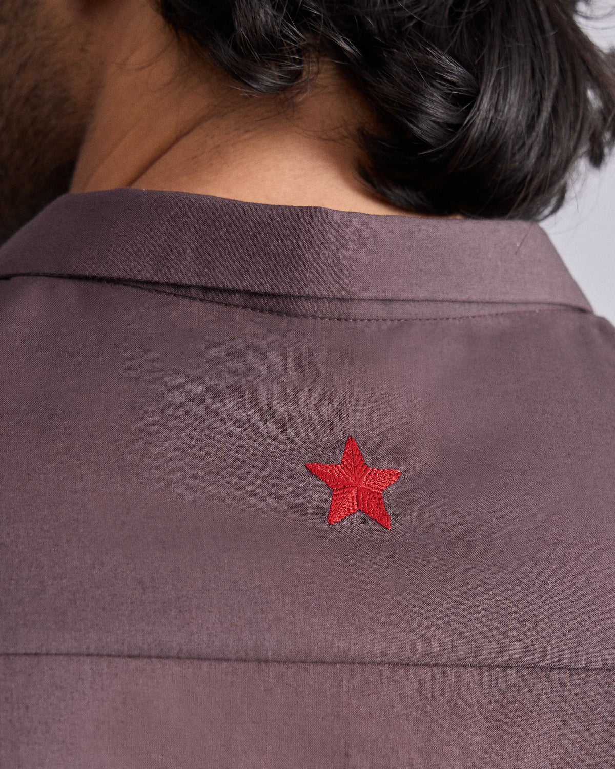 Close-up of a red star embroidered on a chocolate plum Riverine shirt.