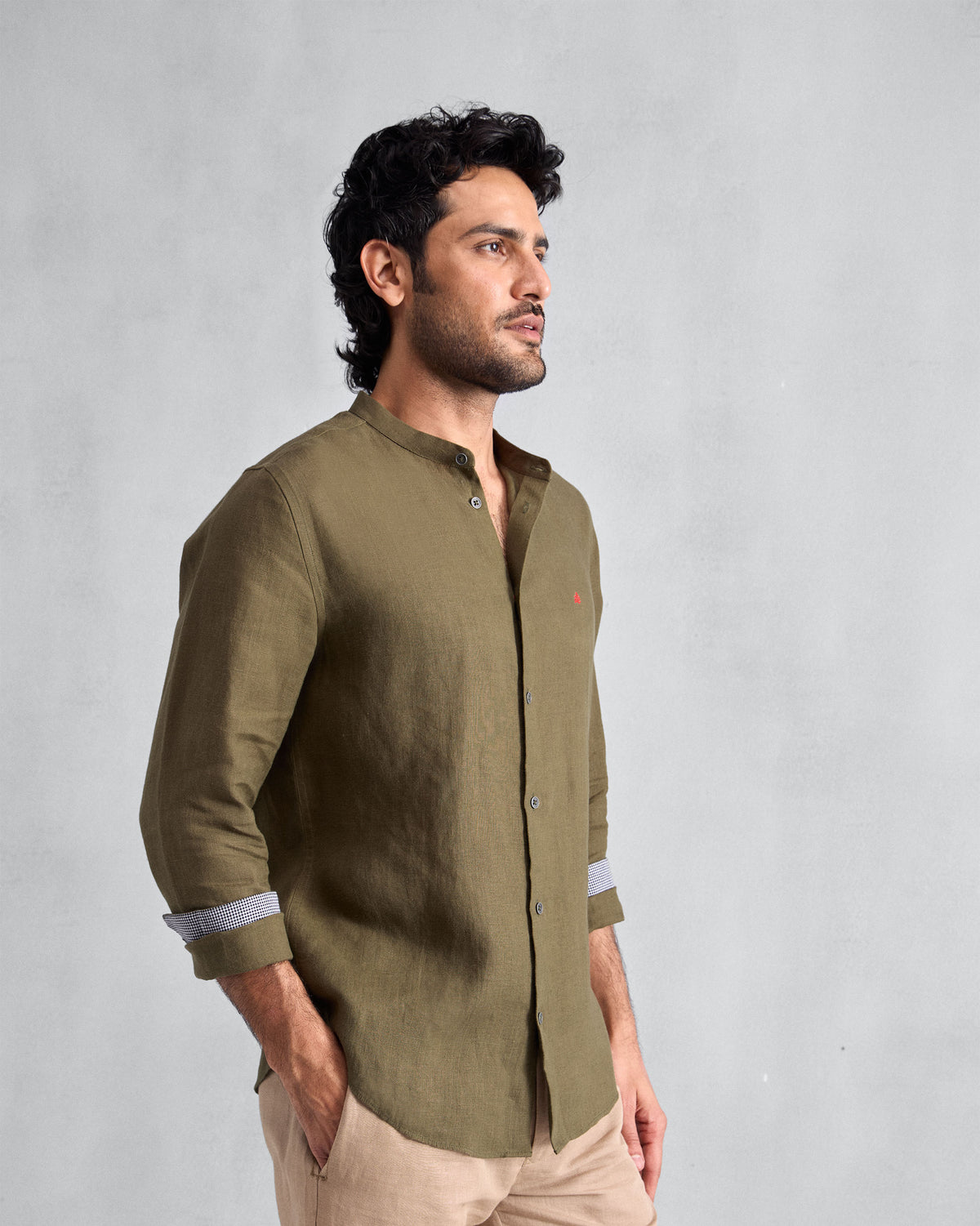 Three-quarter view of an olive Nawab Shirt with rolled sleeves and contrast cuff lining.