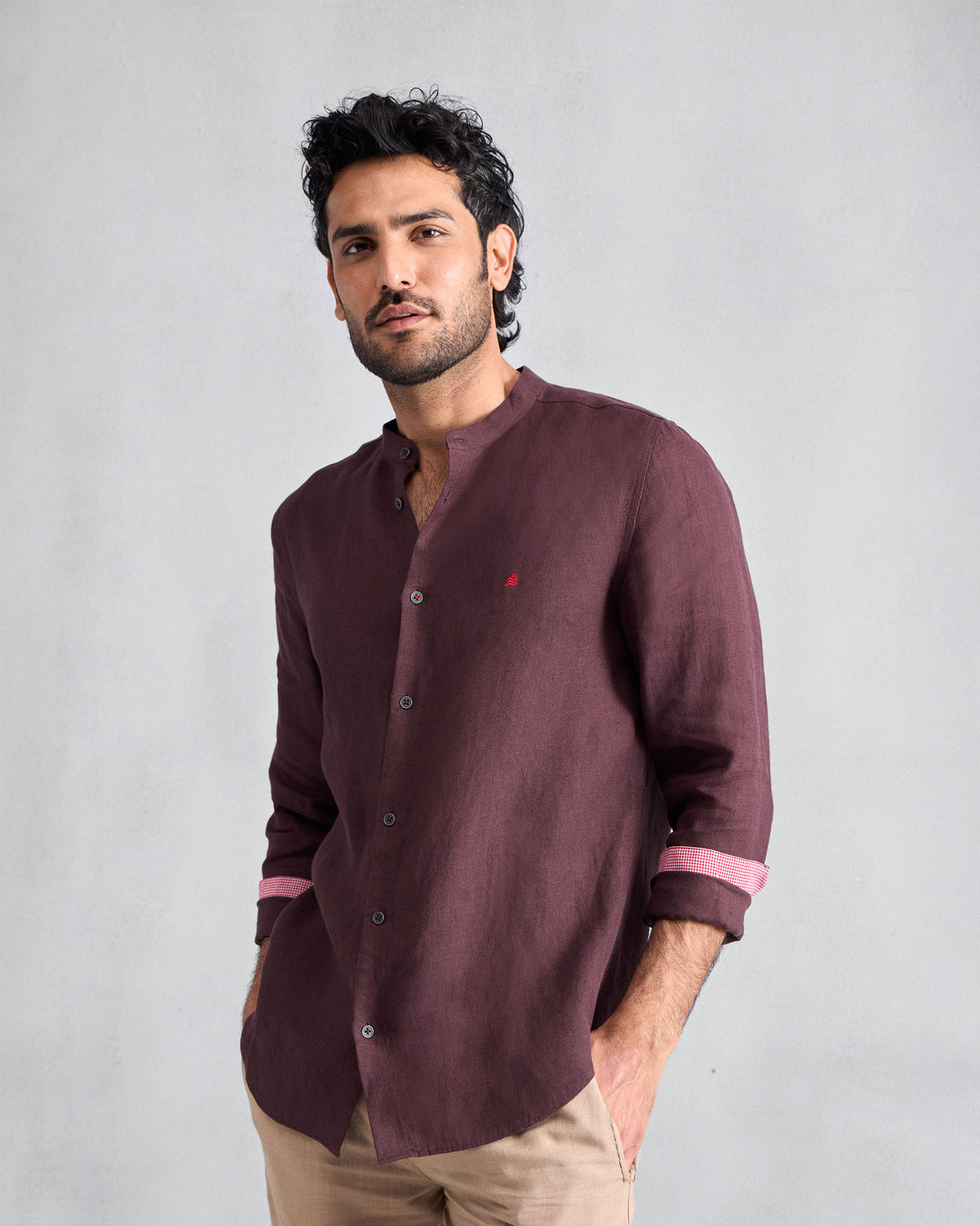 Person wearing a chocolate plum Nawab Shirt with a Nehru collar and pink cuff lining.