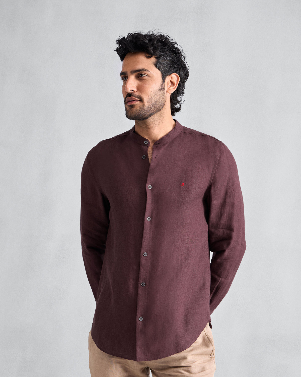 Person wearing a chocolate plum Nawab Shirt with a Nehru collar and red chest logomark.
