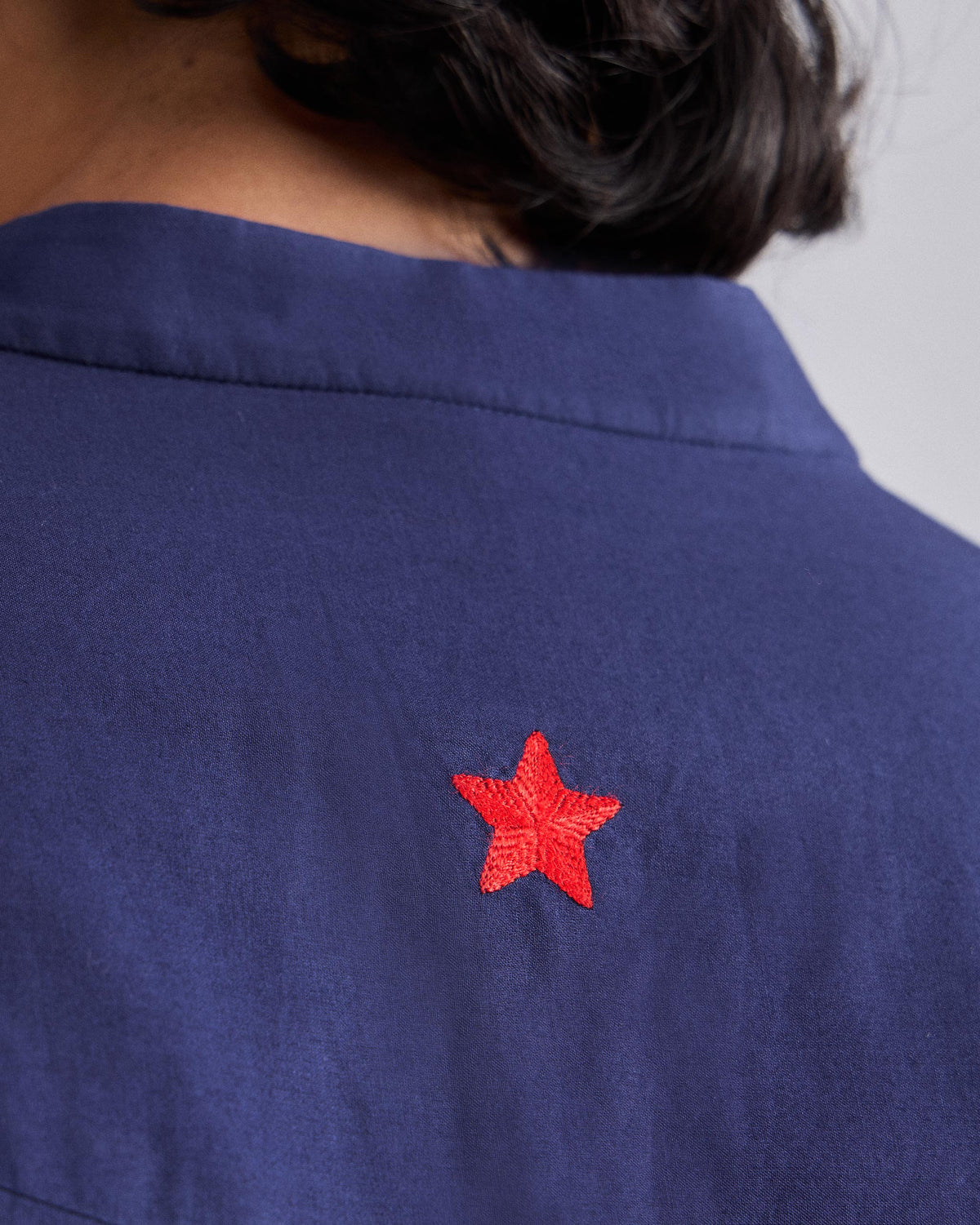 Close-up of a red star embroidered on the back of an ink blue Pondicherry Kurta.