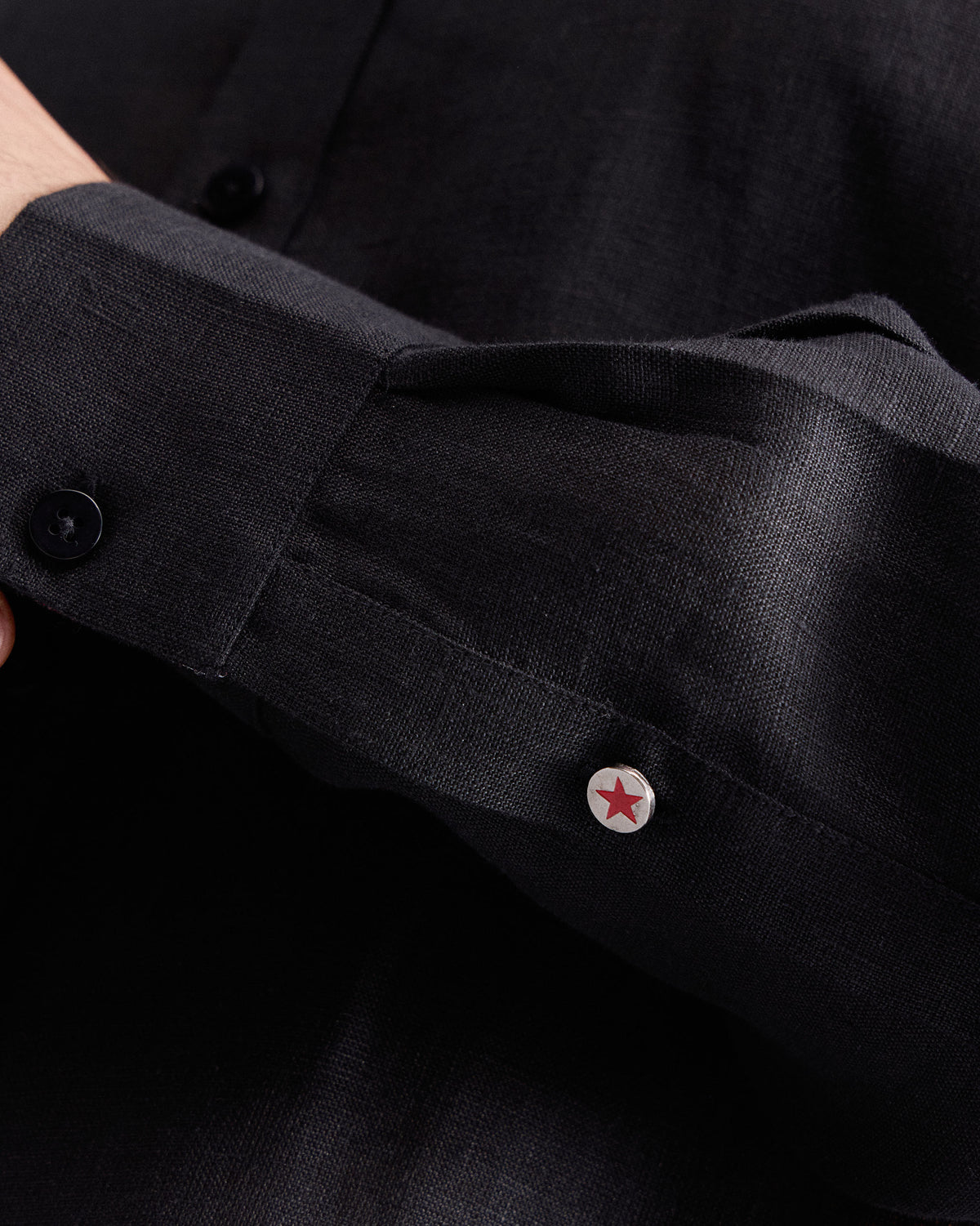 Close-up of a black Classic shirt cuff with a star button.