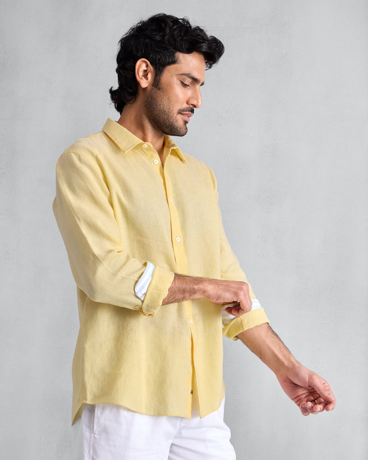 Person rolling the sleeve of a lemon Classic shirt to show striped lining.