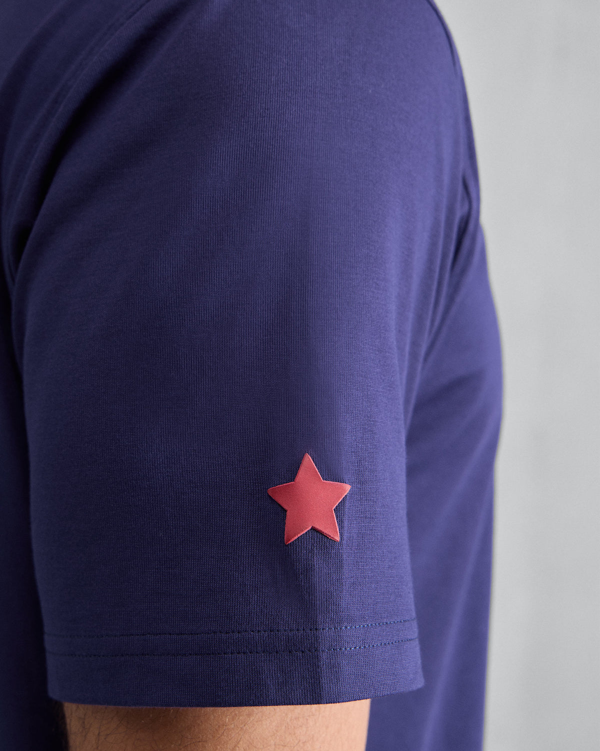 Close-up of a red star on the sleeve of an ink blue Everyday T-shirt.