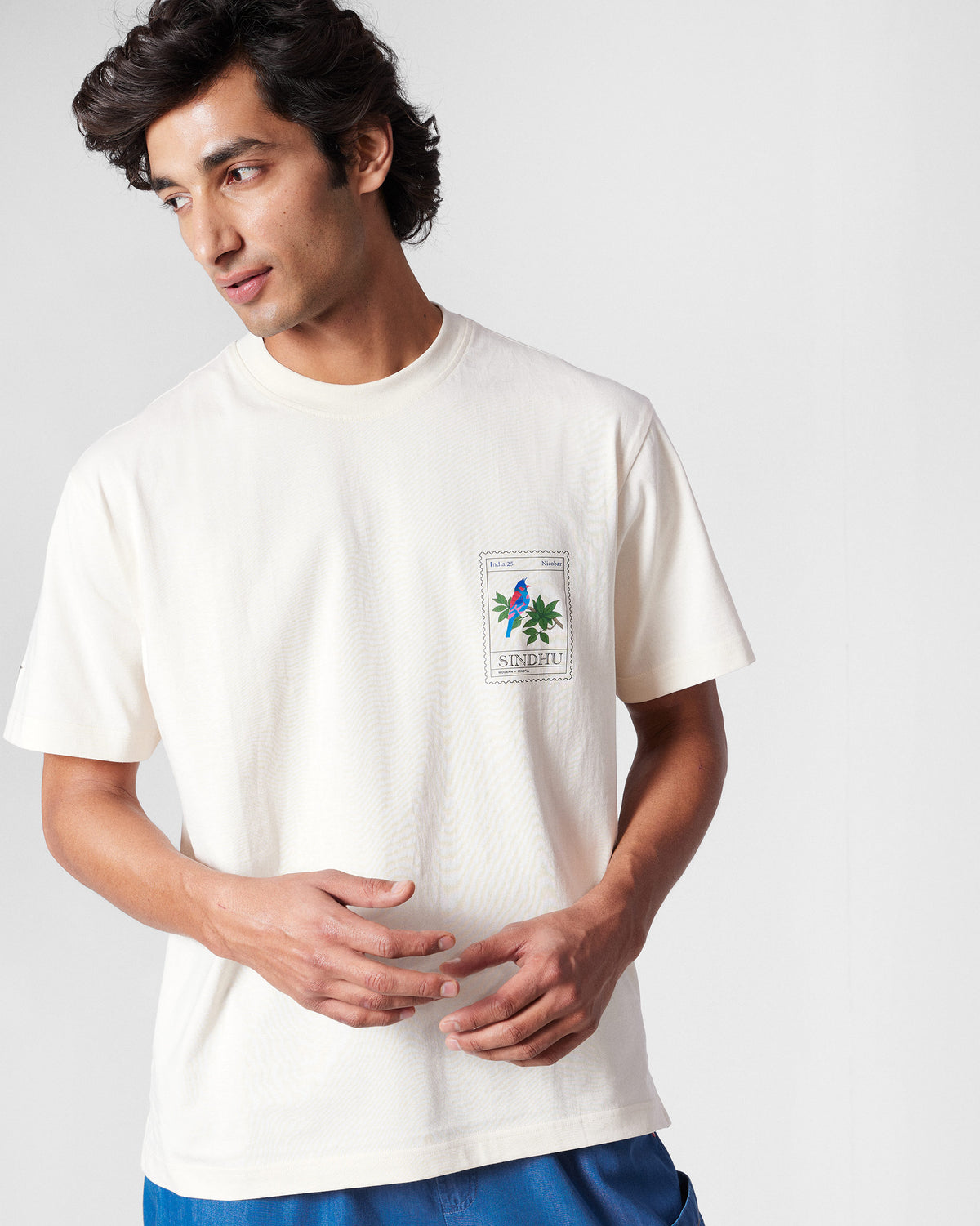 Person wearing an ivory Bulbul t-shirt with a bird stamp at the chest.