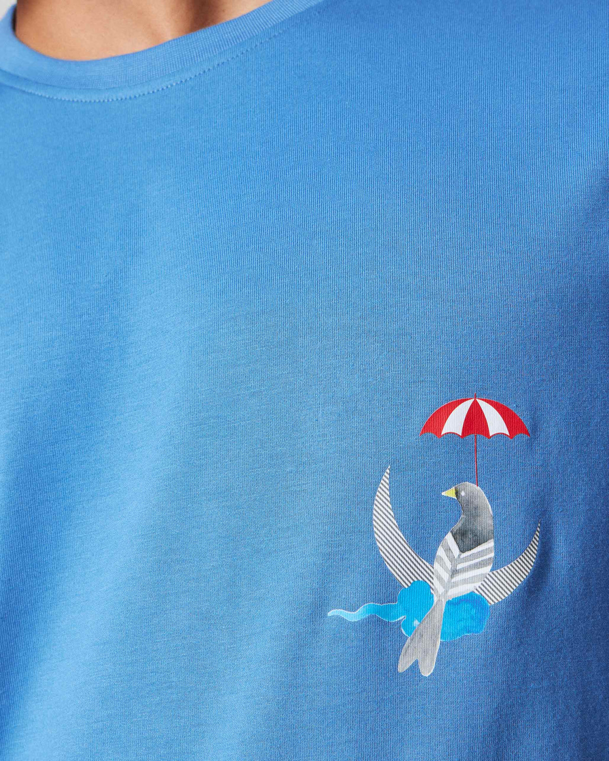 Close-up of a bird with umbrella and crescent motif on a riverside blue Everyday t-shirt.