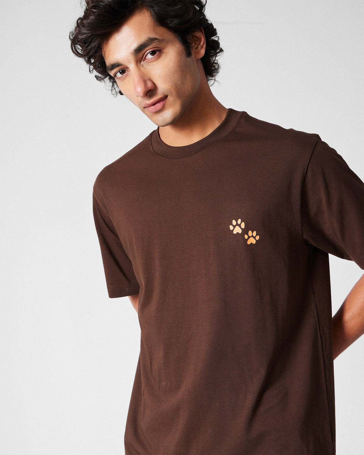 Person wearing a brown Leap t-shirt with peach paw prints on the chest.