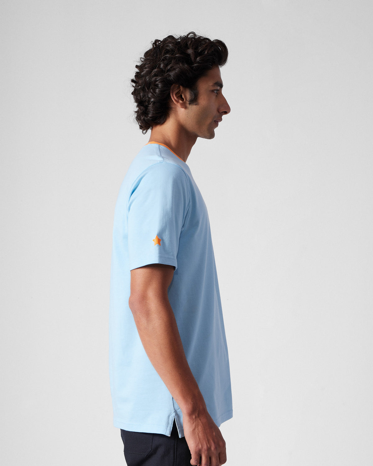Side view of an ice blue Everyday T-Shirt with an orange collar.