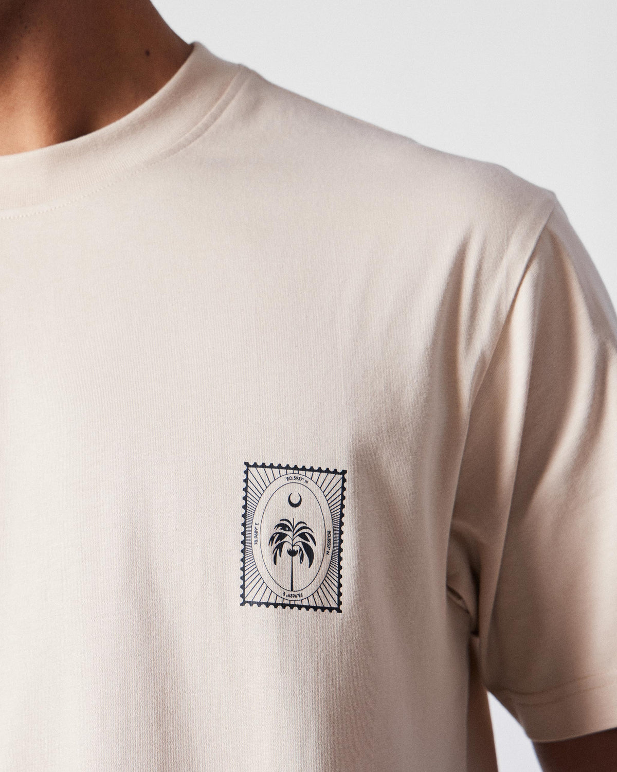 Close-up of a palm and moon postage stamp on a beige Postal T-Shirt.