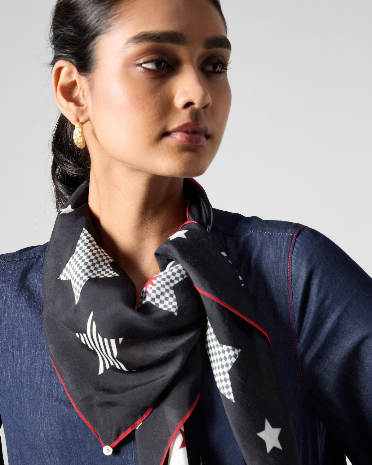 Person wearing a black Starry Night Scarf with white and grey stars and red edging.