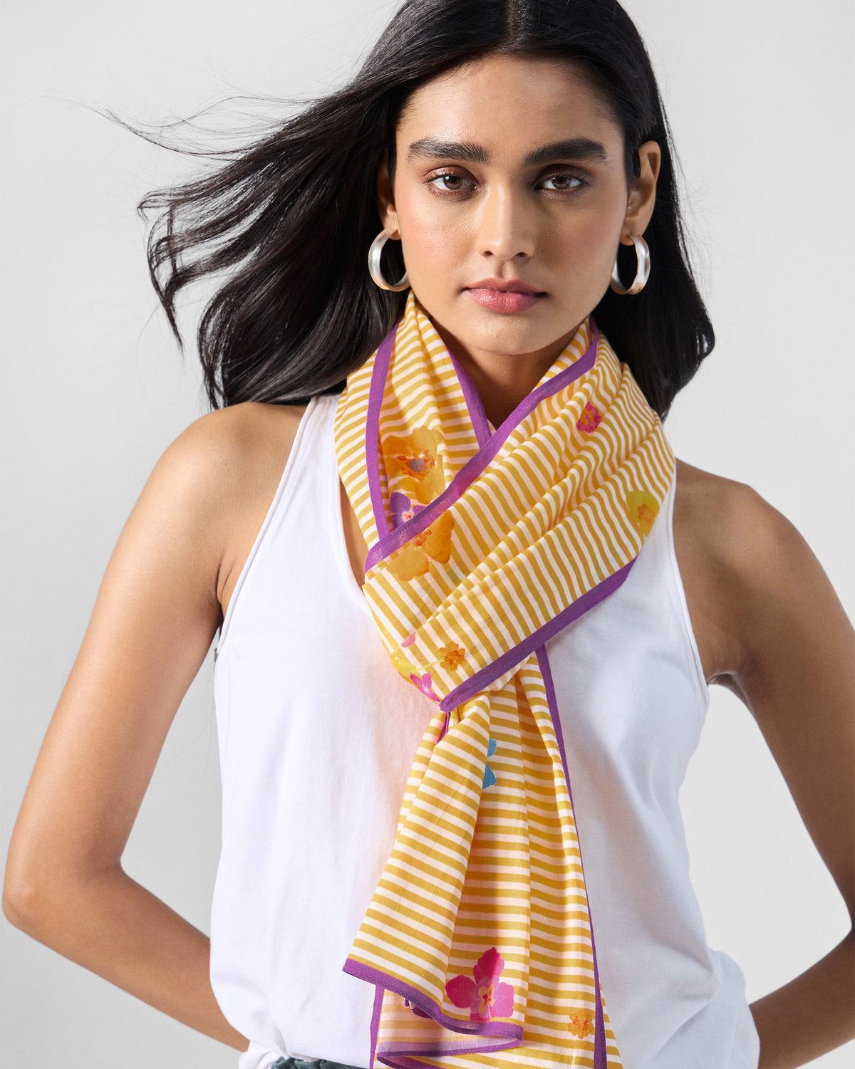 Person wearing the Basant Bloom scarf in yellow stripes with a purple border.