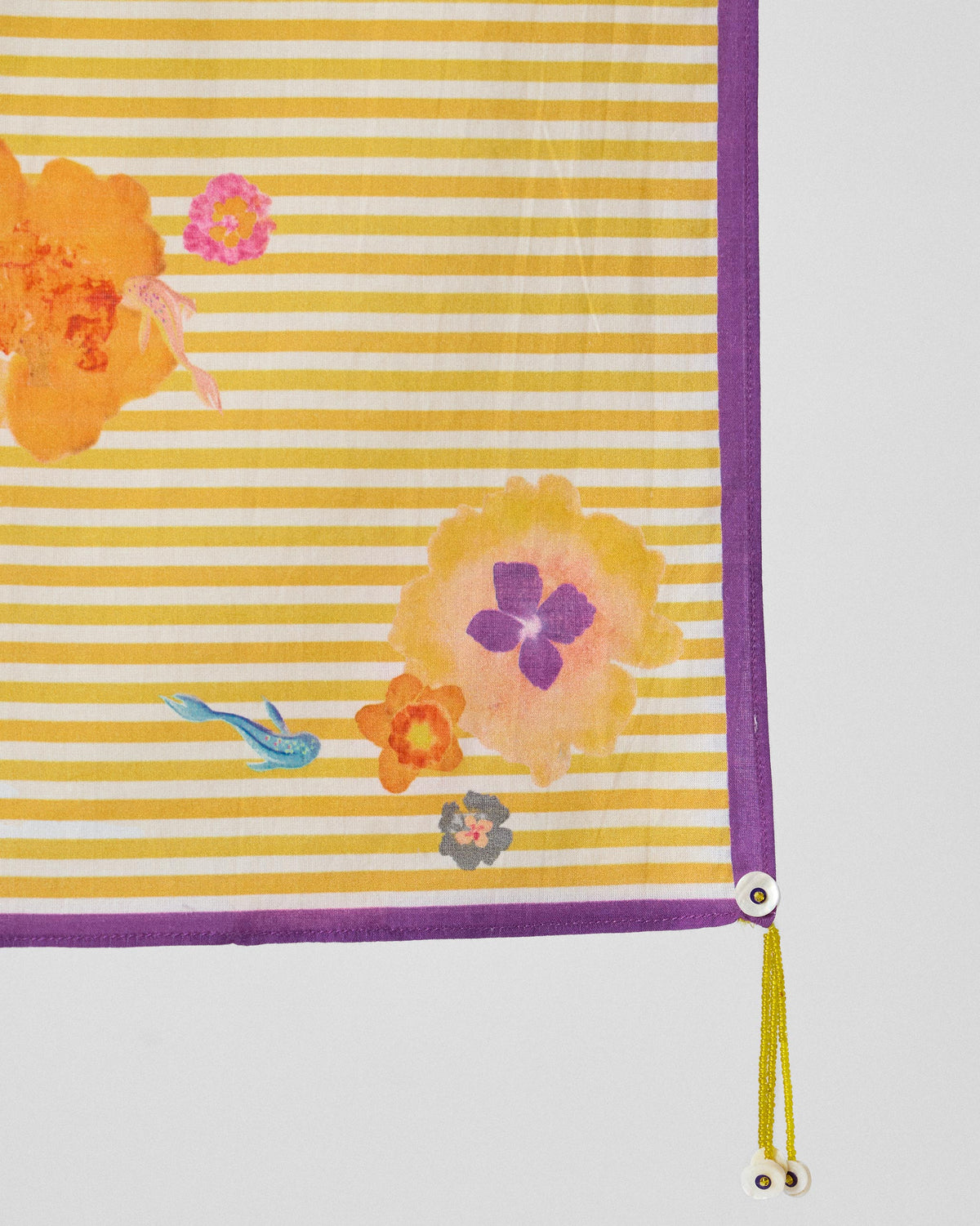 Close-up of the Basant Bloom scarf corner showing flower prints and a beaded tassel.