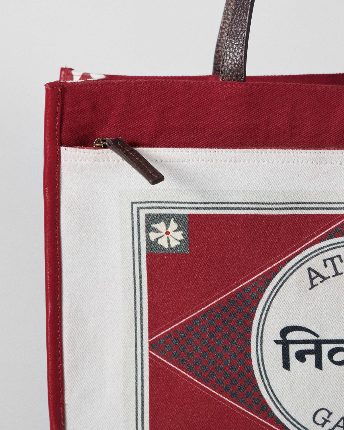 Close-up of the front zip pocket on an ivory and red Ganges tote.