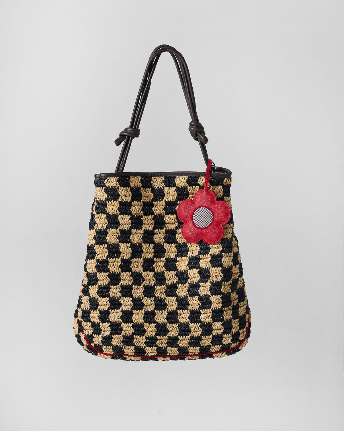 Black and natural check Nomad Tote with brown straps and a red flower charm.