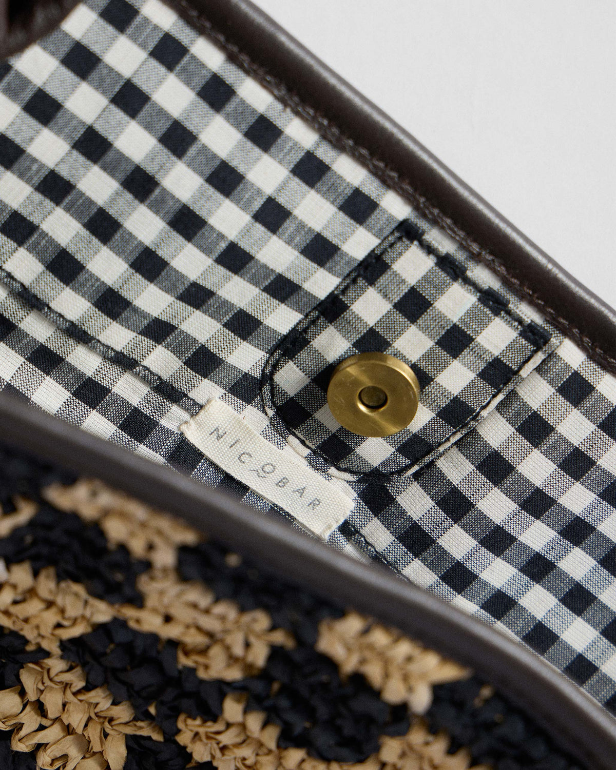 Close-up of the gingham lining and magnetic snap inside a Nomad Tote.