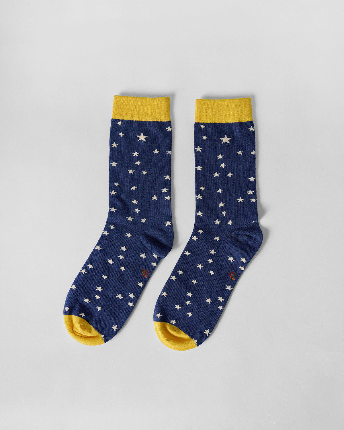 Pair of navy Starry socks with white stars and yellow cuffs laid flat.