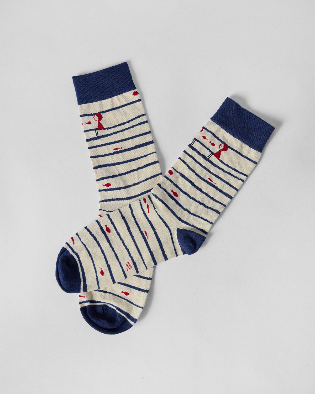 Go Fish socks laid flat at an angle, showing navy stripes and red fish motifs.