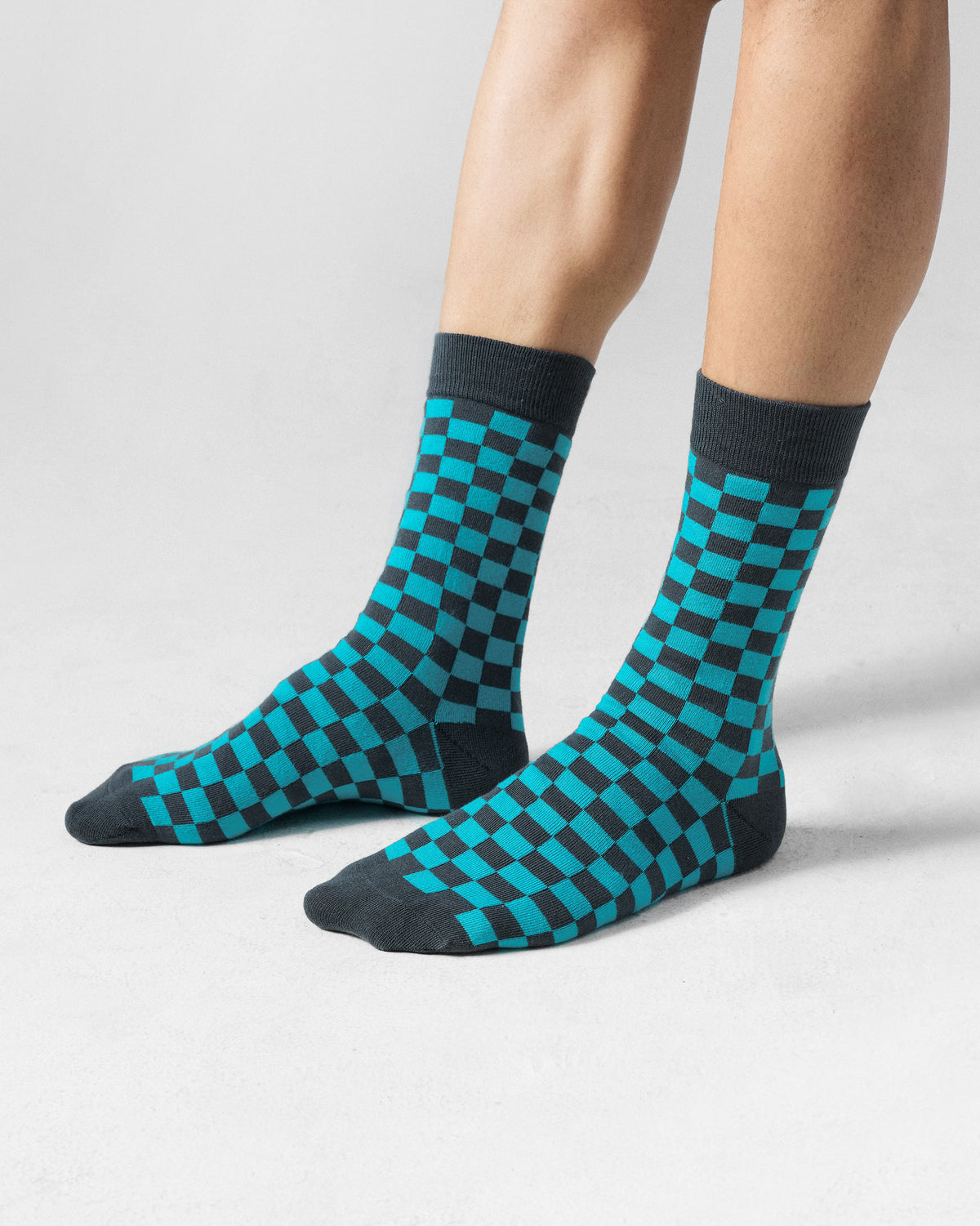 Person wearing teal and charcoal checkerboard Tile Pop Socks.