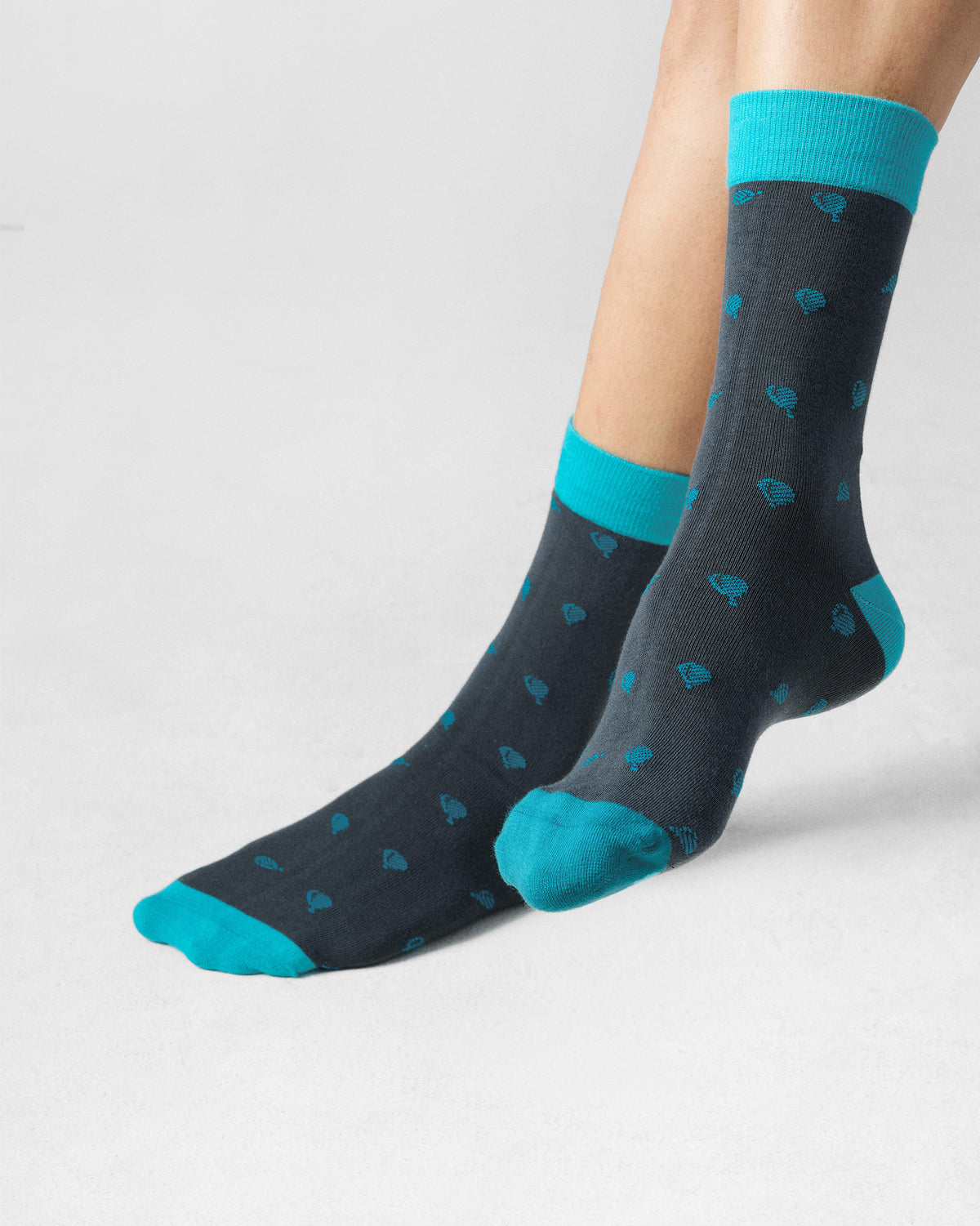 Person wearing charcoal Tile Pop Socks with teal motifs and teal cuffs.