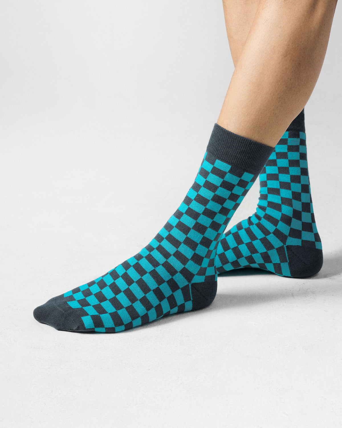 Side view of teal and charcoal checkerboard Tile Pop Socks on a person.