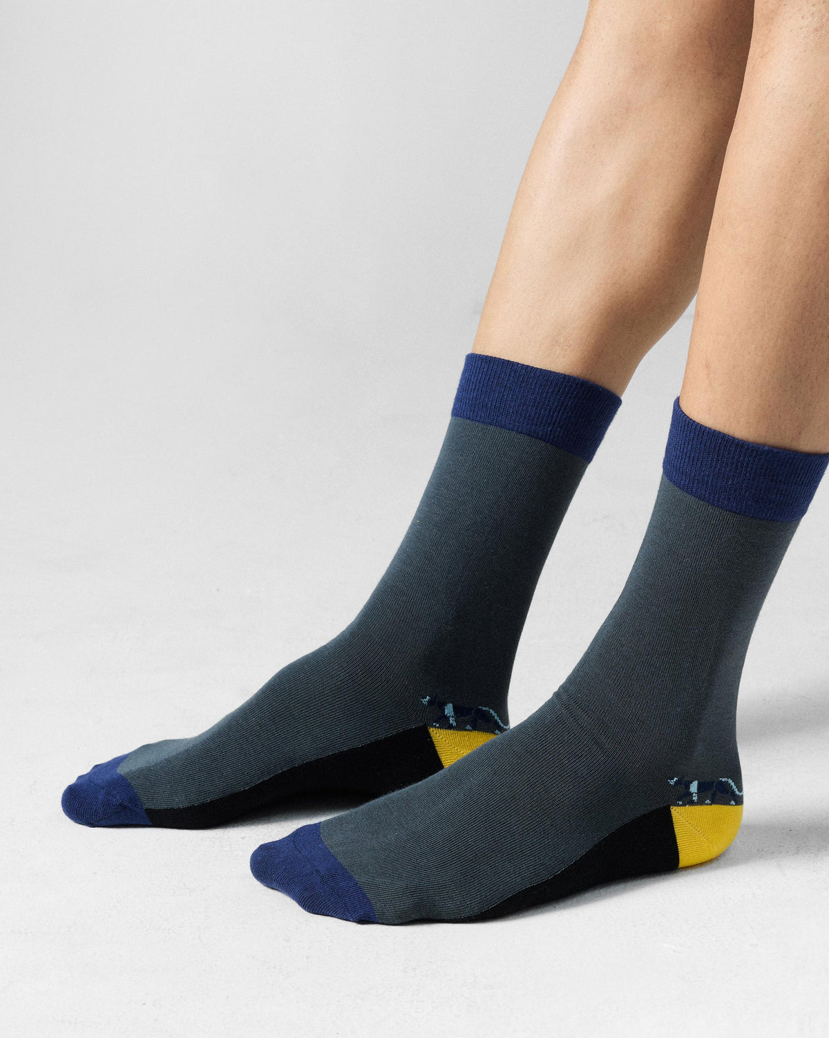 Charcoal Men's Stride Socks with a yellow heel worn on the feet.