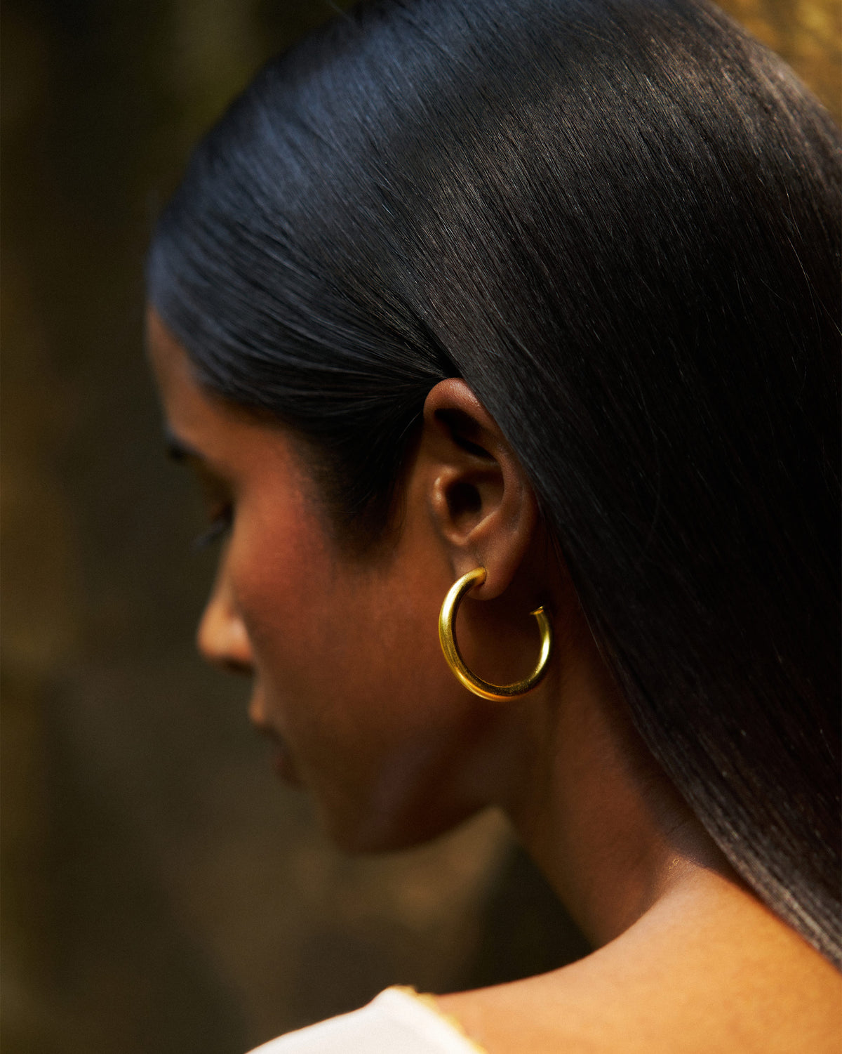 Side profile of gold Everyday Hoops worn on a person.