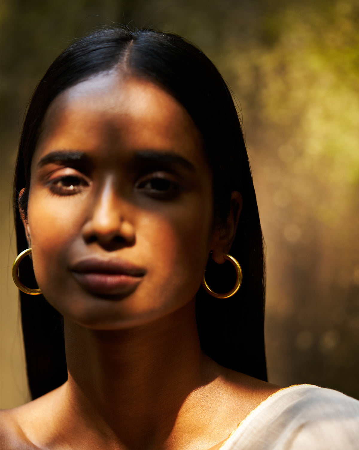 Close-up of a pair of gold Everyday Hoops worn on both ears.