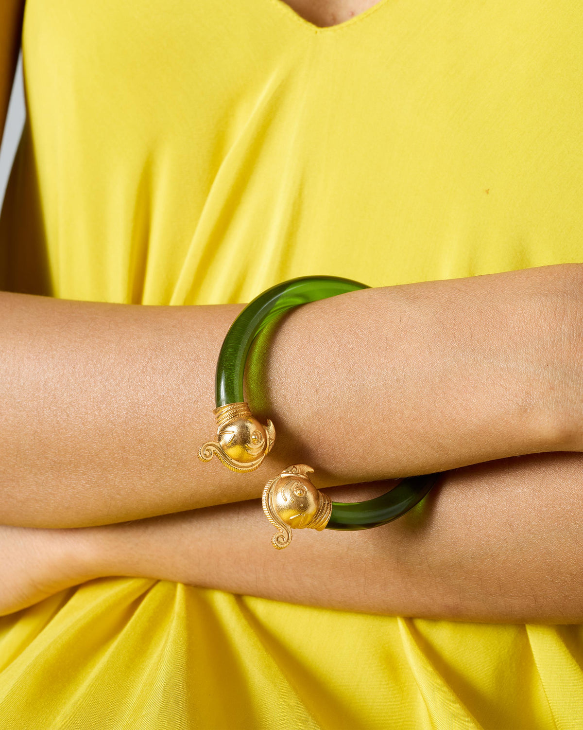 Close-up of a green Mithu bangle with gold parrot ends.