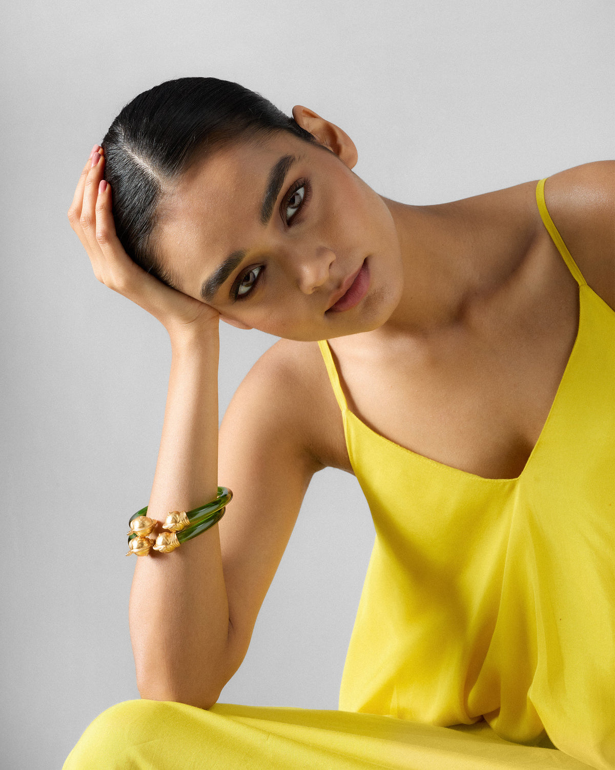 Person wearing green Mithu bangles with gold parrot ends.