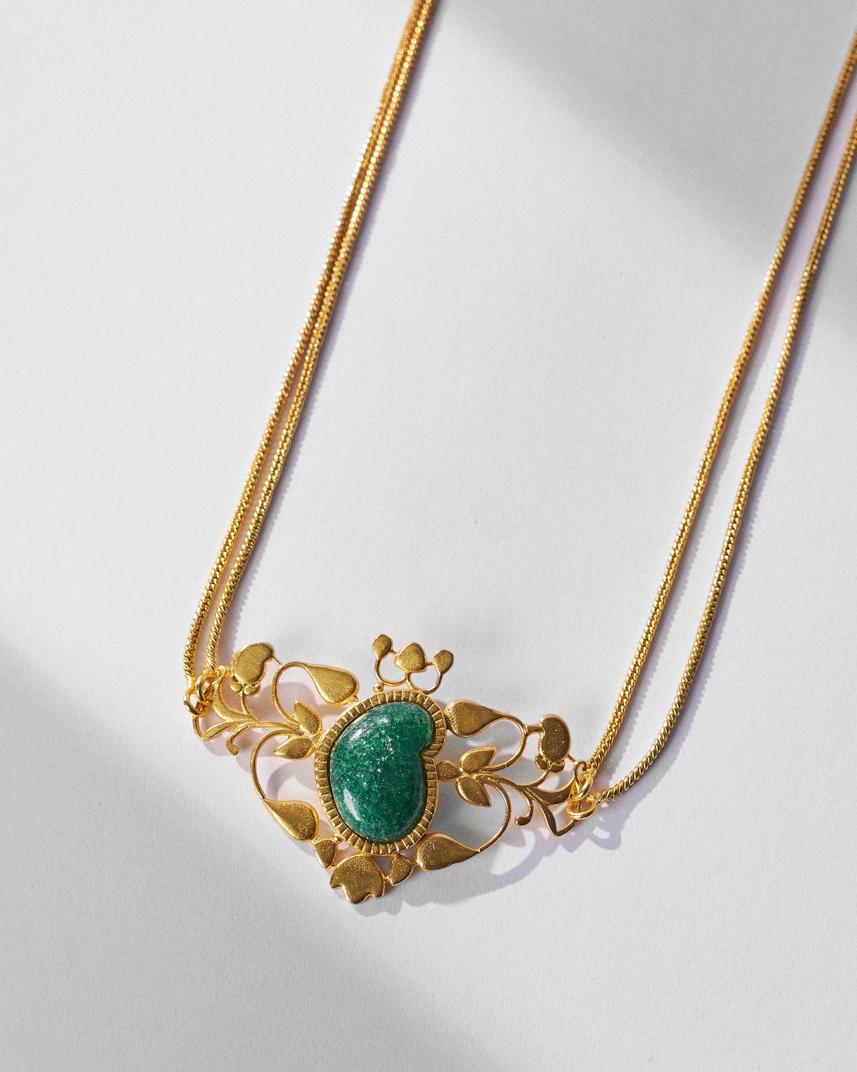 Close-up of the Ambi choker green stone in gold filigree.