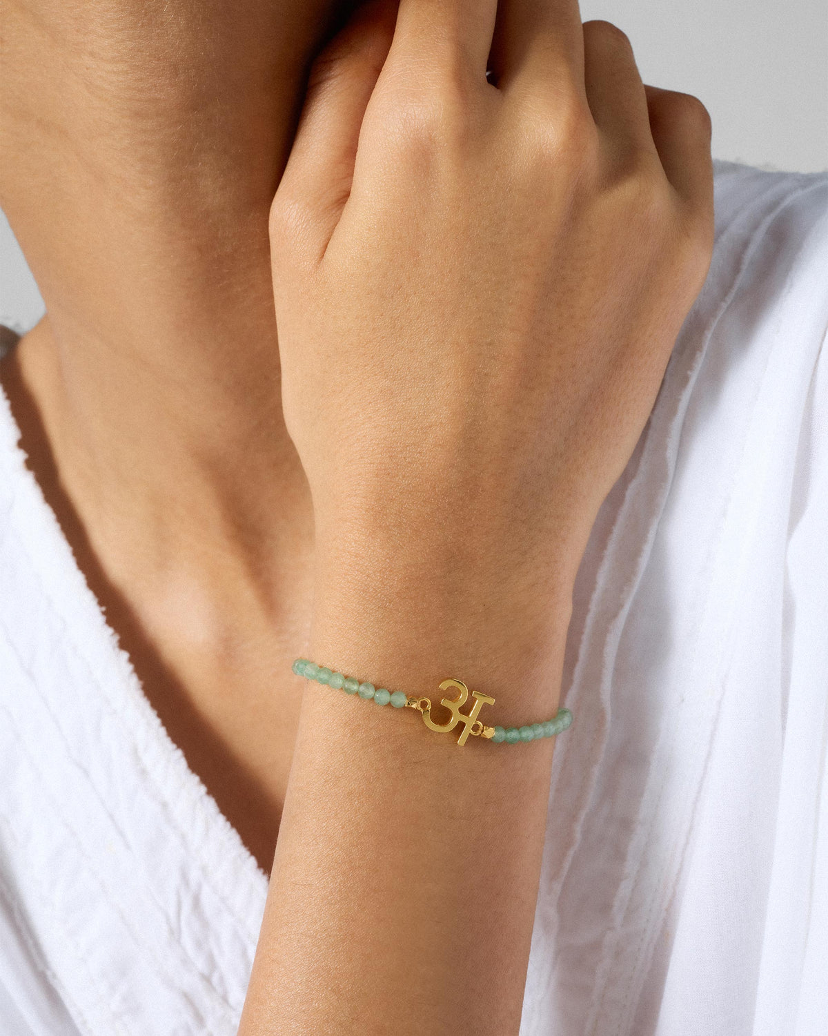 Person wearing Akshar Bracelet (A) - Gold on the wrist.